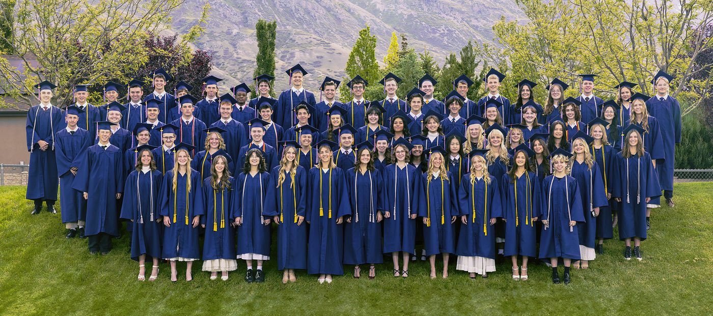 The American Heritage School Class of 2026 in caps and gowns on the campus hillside, mountains behind them