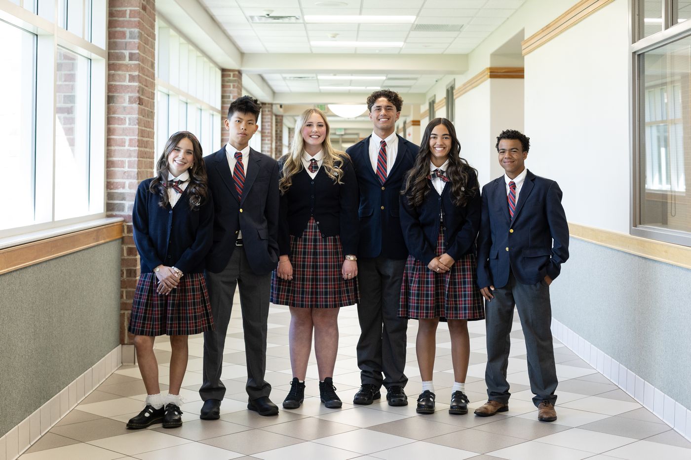 Six American Heritage School high school students in uniform, smiling together in a campus hallway